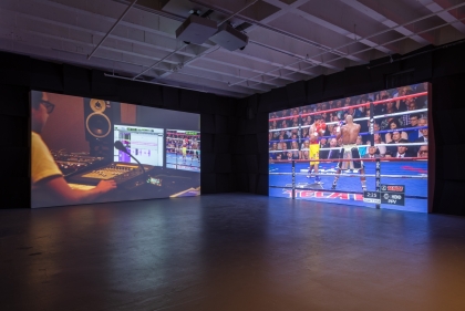 Videos play on two screens in darkened gallery