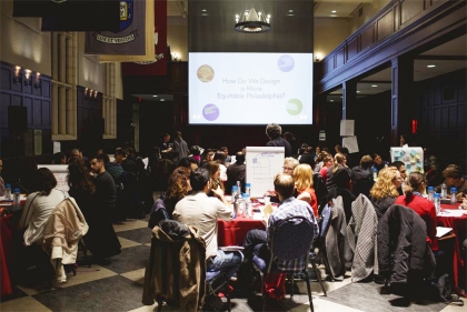 Workshop in progress. Audience seated at tables with projection in background