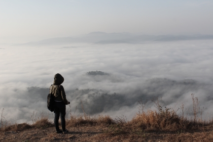 Student on mountain overlooking clouds below