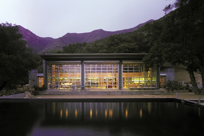 A modern house set next to a swimming pool with mountains in the distance