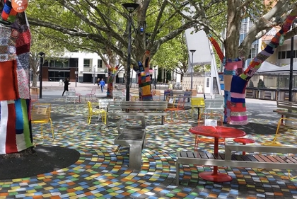 Highly decorated park space. Tree trunks are covered with knitted craft.