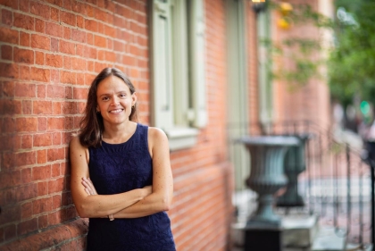 Professor Francesca Russello Ammon leans against a brick rowhouse