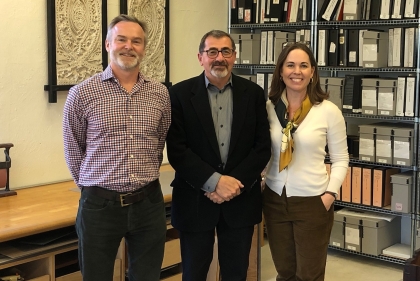 A group of three people in front of a library wall