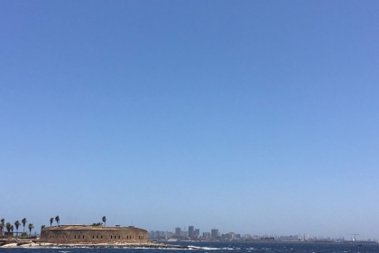 Urban coastline with historic fortress under blue sky