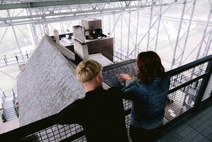 Two people look down on house from a platform at the top of the shelter overtop                          