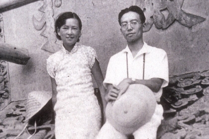 Two young Asian people standing on a tile roof pose for photo