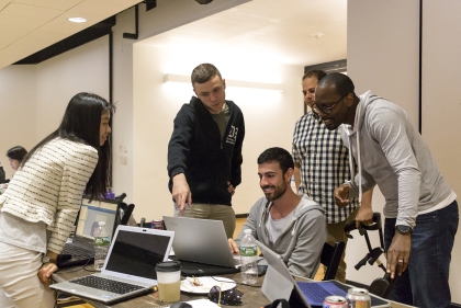 Five students are gathered at a laptop