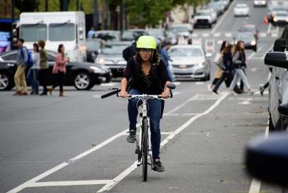 Megan Ryerson wears a helmet outfitted with clear eye-tracking glasses as she travels in a bike lane on a Philly street