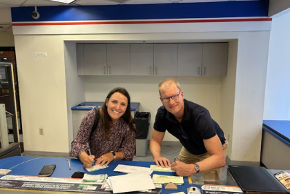 Two people posed signing a letter 