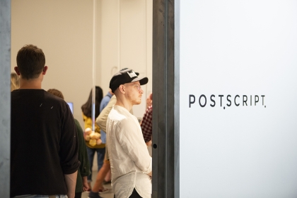 View through doorway to gallery with Postscript lettering on wall to right