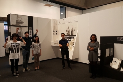 Students standing beside their pieces in gallery display