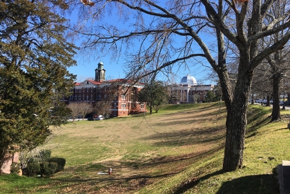 Grassy hills and two stately brick buildings