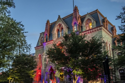 College Hall in the evening time with colored spotlights giving it a dramatic look