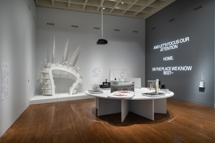 Gallery display with text "And let's focus out attention. Home. On the place we know best." projected on wall