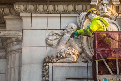 Man restoring detail on stone carving on building