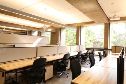 Well lit hall with long desks and rows of swivel chairs by them