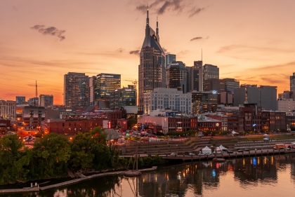 Nashville skyline at dusk showing neon-lit business adjacent to riverfront