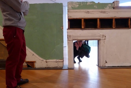 Woman crouching behind tiny doorway in art installation