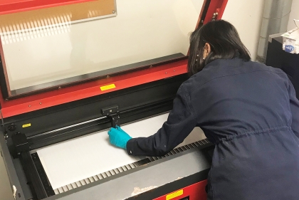 A person cuts plastic using a laser cutter