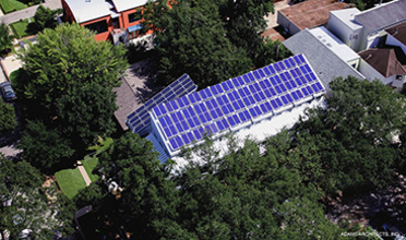 Solar panels cover a rectangular building surrounded by trees
