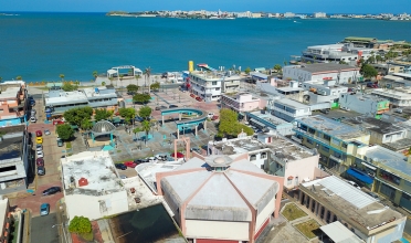 View of The Del Carmen Church from above in front of a plaza & the San Juan bay. 