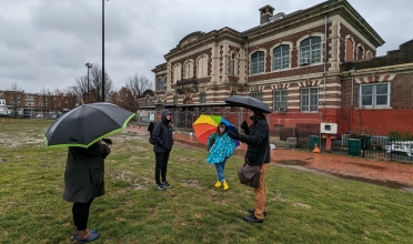 people with umbrellas in grass standing in front of public library