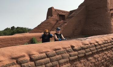 H. Ro and A. Cavicchio applying mud capping on a convento wall, with the Pecos church in the background.