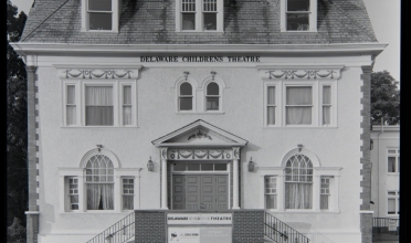 White 3-story facade with sign "Delaware Childrens Theatre" in B&W photograph