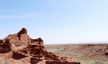 Brick-red structure/ruin overlooking desert landscape