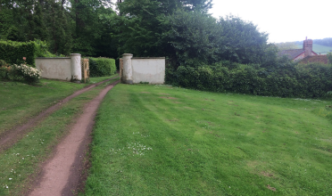 Carriage trail leading to garden entrance framed with two white pillars