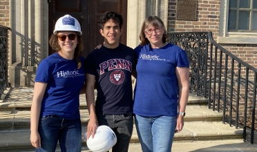 Three people pose in front of brick building