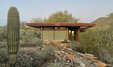 small modernist structure in desert with cactus in foreground