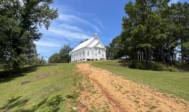 white church building, dirt path, and trees