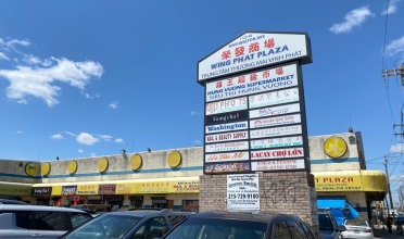 large sign in parking lot of strip mall with yellow awnings