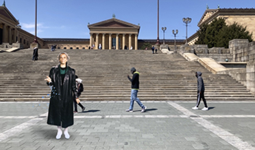 A woman in black attire stands on an outdoor staircase with the museum in the background