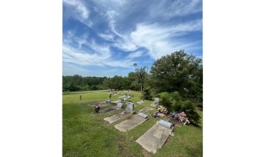 Grave markers in historic parish cemetery terracing down back hill of property looking west.