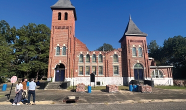 studio team stands in front of partially demolished church