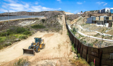 Bulldozer in desert next to fence