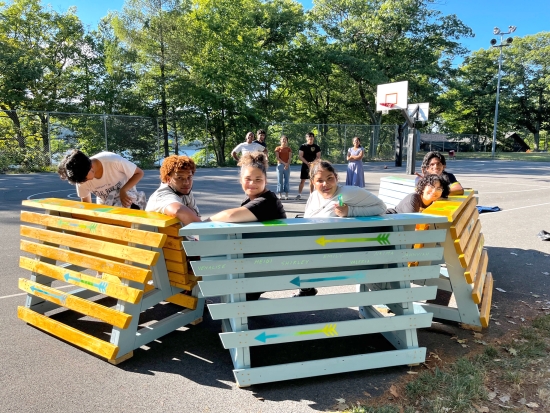 A group of students sitting on benches turn to face the camera