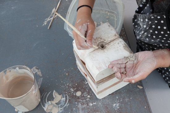 Close up of student working with clay using a press mold.