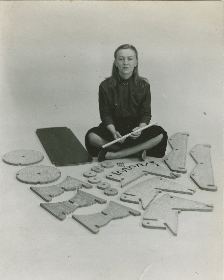 Anne Griswold Tyng sitting on floor surrounded by wooden cutouts