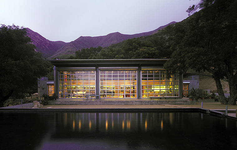 A modern house set next to a swimming pool with mountains in the distance