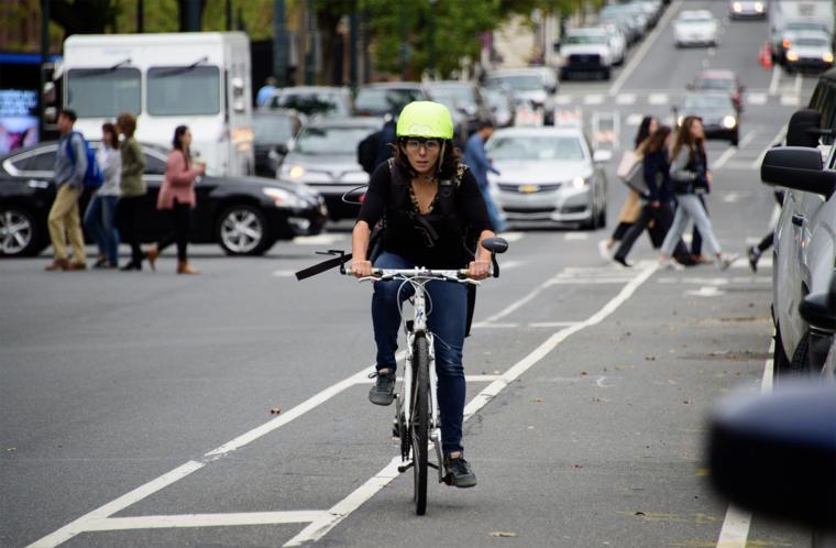 Megan Ryerson wears a helmet outfitted with clear eye-tracking glasses as she travels in a bike lane on a Philly street
