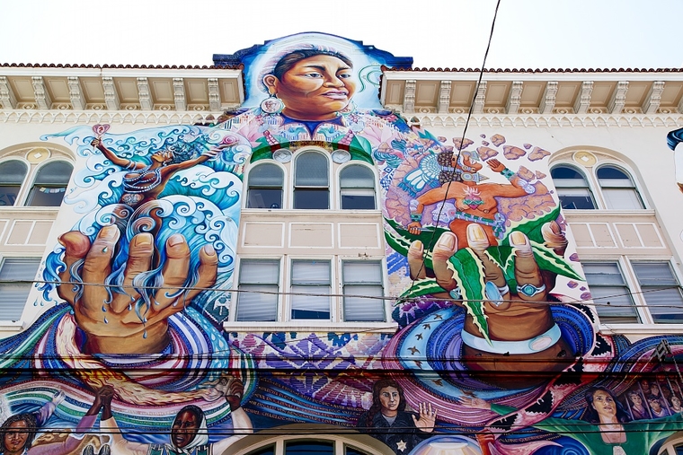 Multicolor mural depicting a smiling woman holding animated figures