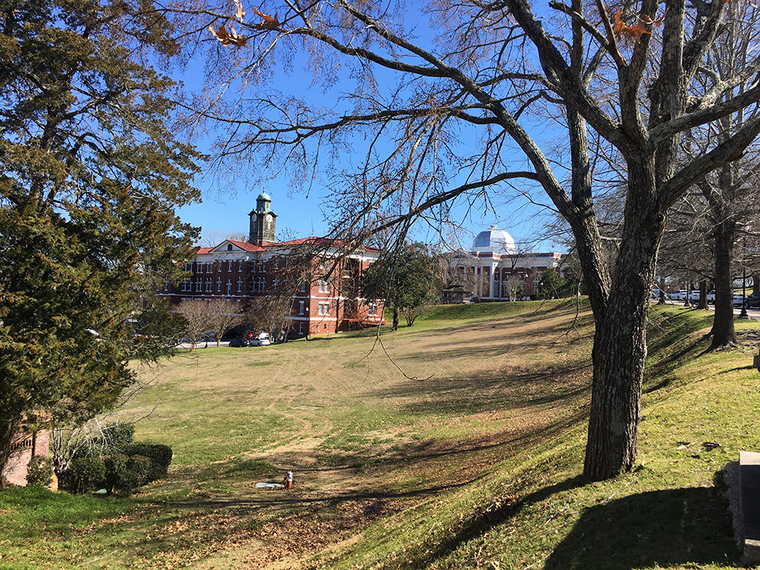 Grassy hills and two stately brick buildings