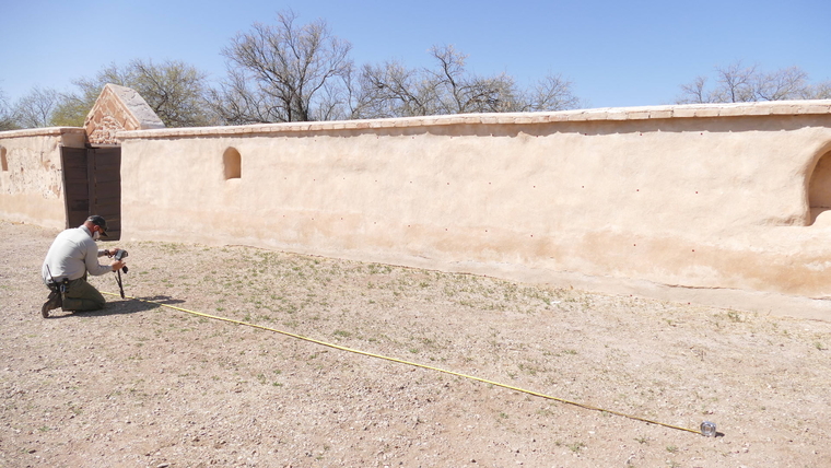Man photographing adobe wall