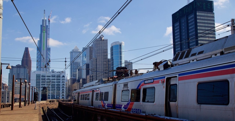 A regional rail train entering a station with skyline in background