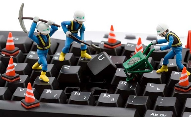 Keyboard with plastic construction worker toys on it 'working' on one of the keys