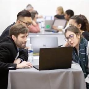 Two people looking a laptop computer screen