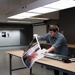 Young man handles photo print in lab